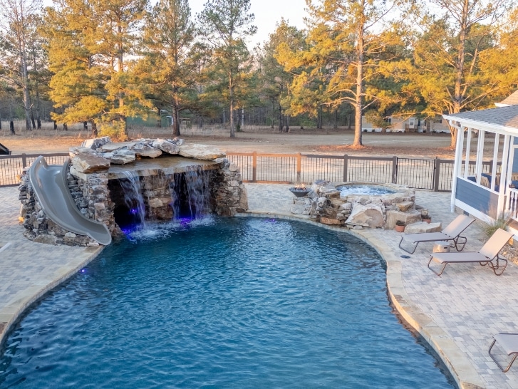 lake country pools project with hot tub, fire features, a grotto, slide, and waterfalls