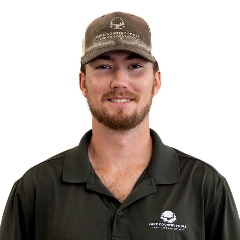 A man with a beard wearing a dark polo shirt and a matching cap, both featuring a Lake Country Pools and Outdoor Living logo, standing against a plain white background, smiling at the camera.