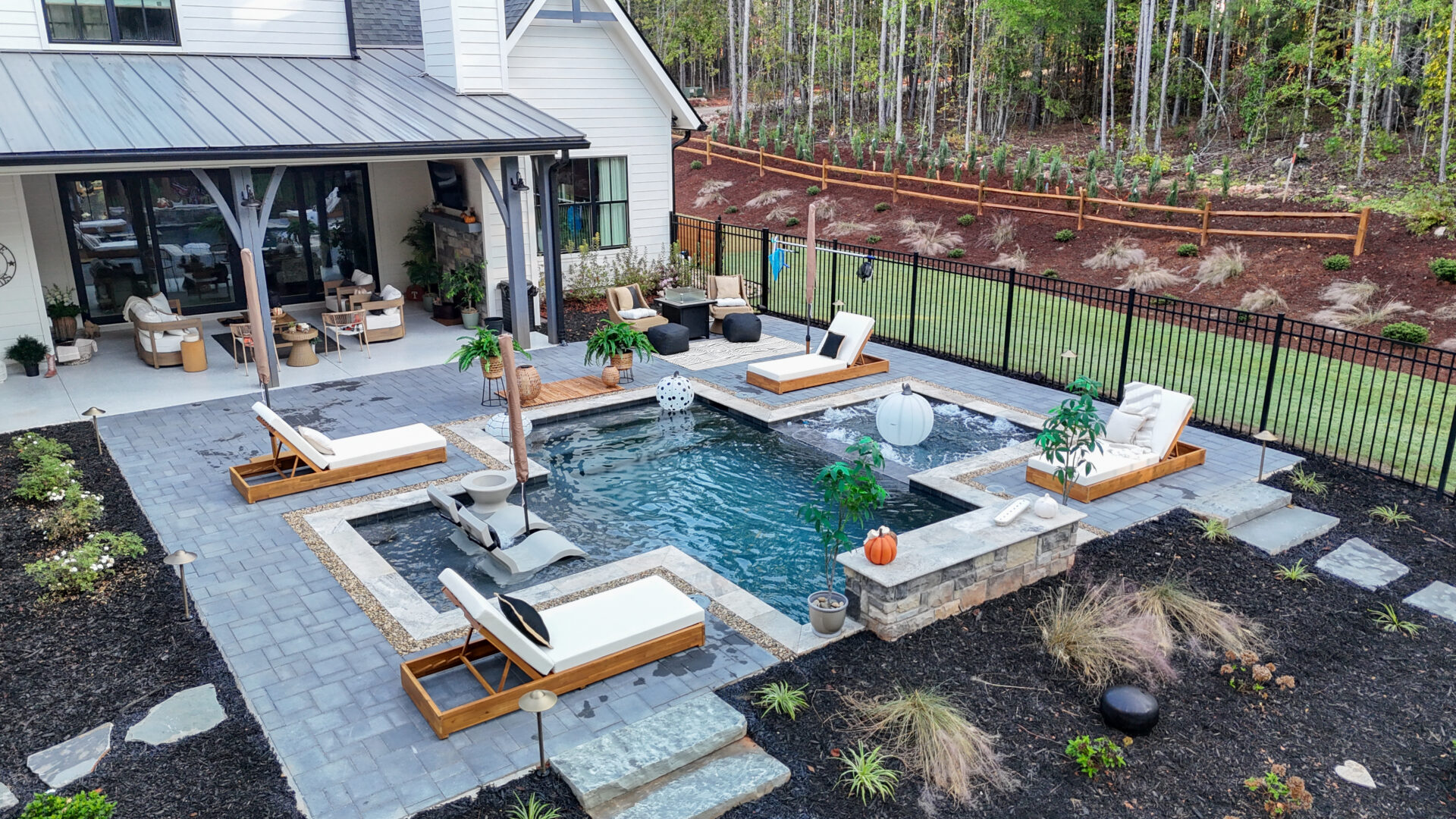 Backyard patio featuring a swimming pool with multiple lounge chairs and an attached hot tub.